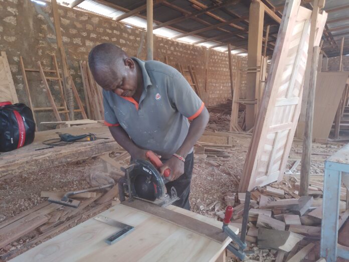 James Mua, disabled, showcases his skills in his workshop. James Mua specializes in boat making making him get money for his family who are disabled too .Photo Courtesy Teryani Mwadzaya